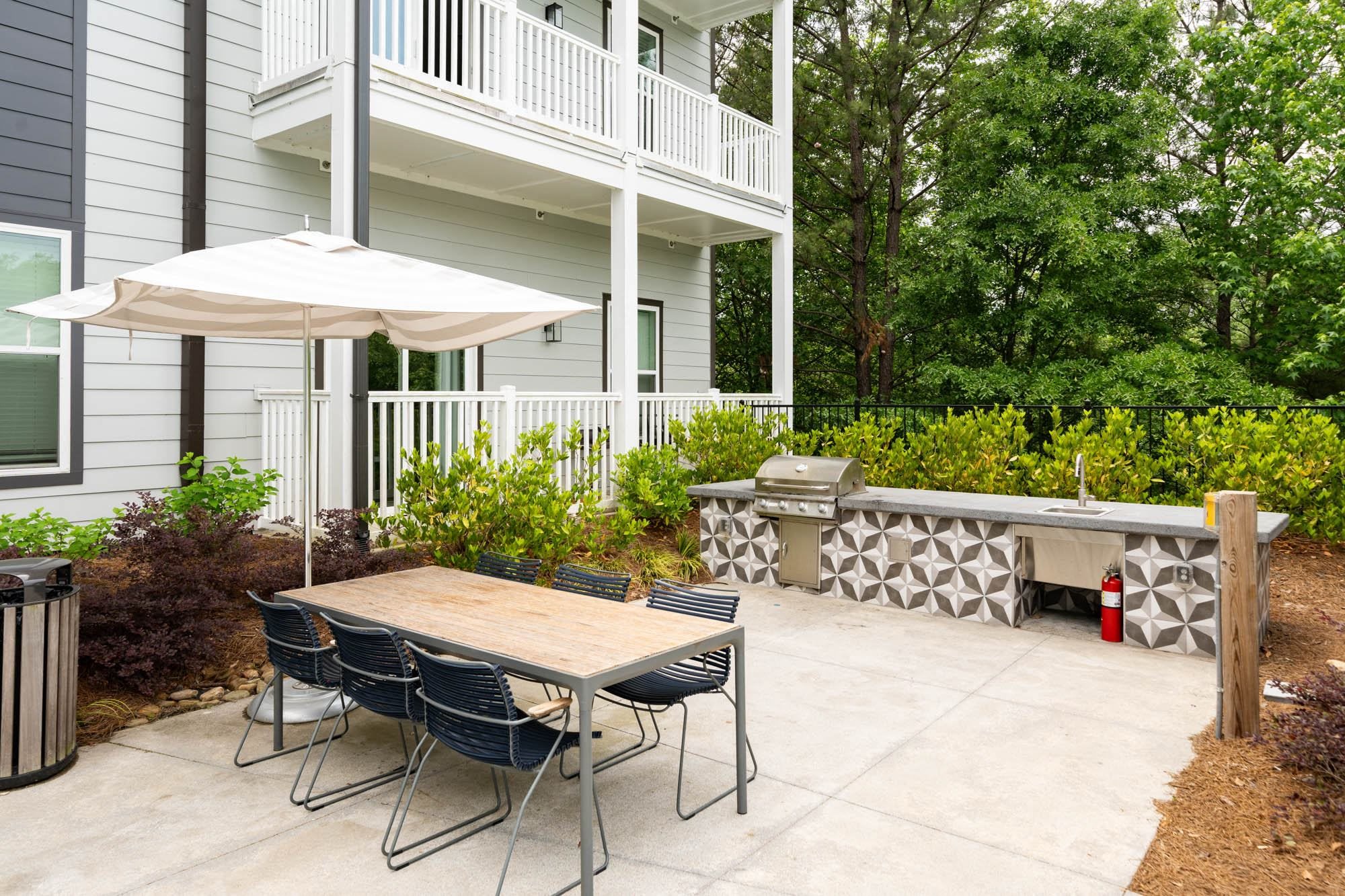 a patio with a table and chairs and an umbrella in front of a house